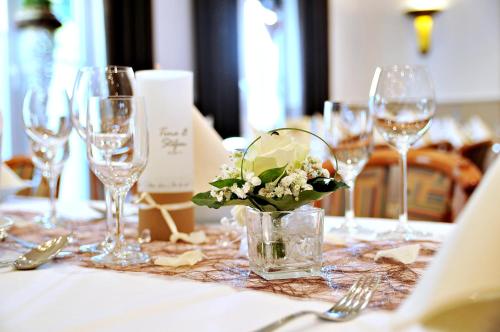 - une table avec des verres à vin et un vase avec des fleurs dans l'établissement Hotel Restaurant Bürgerklause Tapken, à Garrel