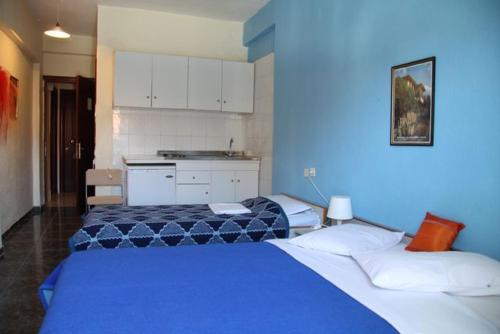 two beds in a room with blue walls at Hotel Dias Apartment in Makrýgialos