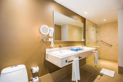 a bathroom with a sink and a mirror and a toilet at Cosmos Pacifico Hotel in Buenaventura