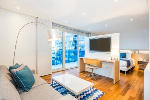 a living room with a couch and a desk with a television at Cosmos Pacifico Hotel in Buenaventura