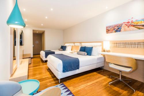 a hotel room with two beds and a desk at Cosmos Pacifico Hotel in Buenaventura