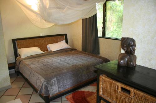 a bedroom with a bed and a statue on a table at Hotel Napoleon Lagune in Lomé