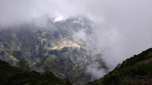 a misty mountain with a town on top of it at Ape Esquerdo in São Vicente