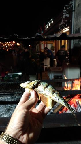 a person holding a piece of food in front of a grill at Ape Esquerdo in São Vicente