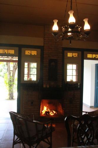 a fireplace in a living room with chairs and a fire place at Pousada do Canto in Rio Acima