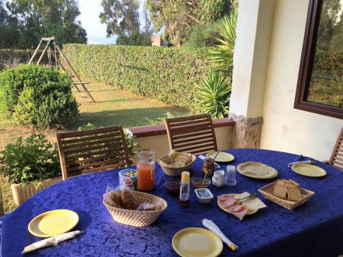 una mesa azul con comida y cestas en ella en B&B Casa Vacanze La Mimosa Alghero, en Porto Conte