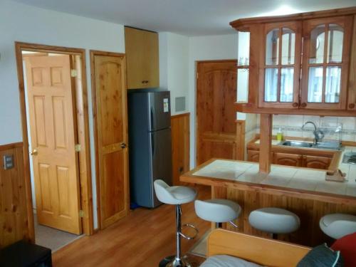 a kitchen with a refrigerator and stools in a room at Depto Parque Suizo 800 in Pucón