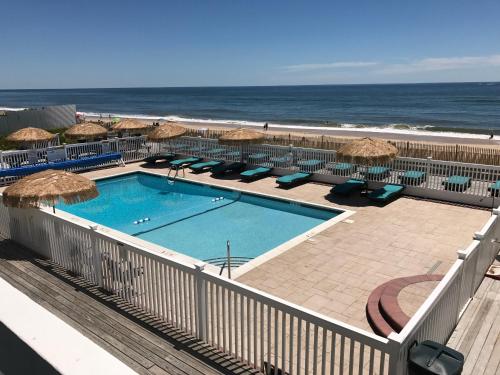 a swimming pool with umbrellas and chairs and the beach at Ocean Surf Resort in Montauk