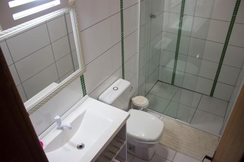 um banheiro com vaso sanitário, pia e chuveiro em Pousada Suites do Santinho em Florianópolis