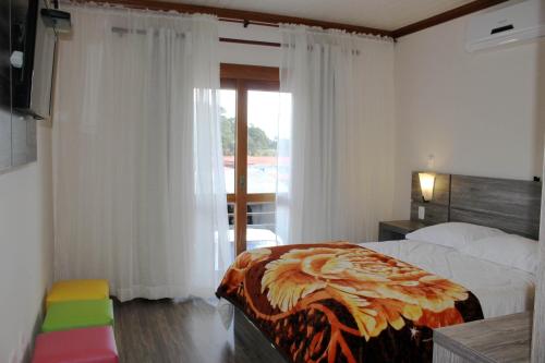 a bedroom with a bed and a window at Residencial Aconchego do Lago in Gramado