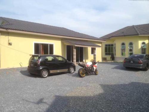 a car and a motorcycle parked in front of a house at Hajjah Norma Homestay in Kangar