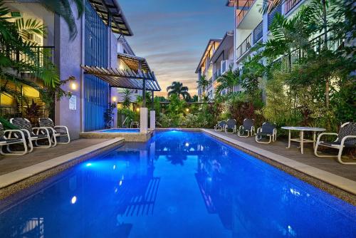 a swimming pool with chairs and a table next to a building at Getaway On Grafton in Cairns