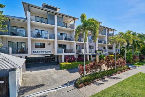 an apartment building with palm trees in front of it at Getaway On Grafton in Cairns