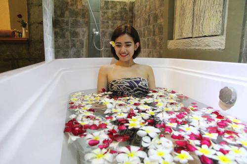 勒吉安The Jayakarta Bali Beach Resort的坐在浴缸里的女人,在花上盛放一个大蛋糕