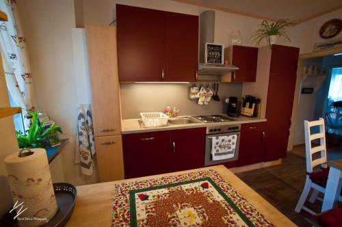 a kitchen with red cabinets and a table with a rug at Quilt Inn in Baumholder
