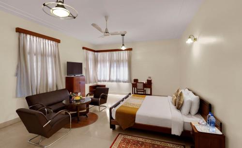a bedroom with a bed and a table and chairs at Hotel Sunderban Resort & Spa in Pune