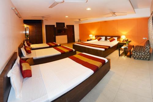 a hotel room with three beds in a room at Hotel Palace in Amritsar