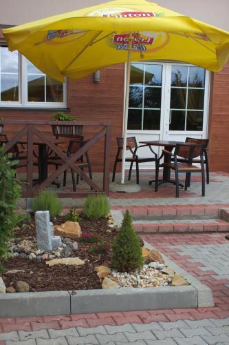 a patio with a table and a yellow umbrella at Hotel Pod Złotą Koroną in Opole