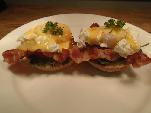 Dos sándwiches de desayuno con tocino y queso en un plato. en Tadrai Island Resort, en Isla Mana