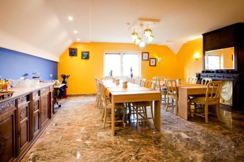 uma sala de jantar com paredes amarelas e mesas e cadeiras de madeira em Shangrilaherzele em Herzele