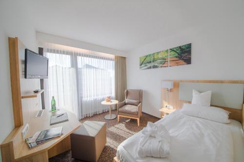 a hotel room with a bed and a desk at Wellness Hotel Harms in Bad Nenndorf