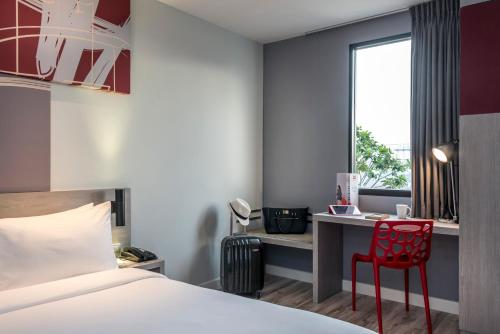 a bedroom with a bed and a desk and a red chair at ibis Bangkok IMPACT in Nonthaburi