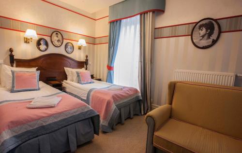 a hotel room with two beds and a chair at Hotel St. Bruno in Giżycko