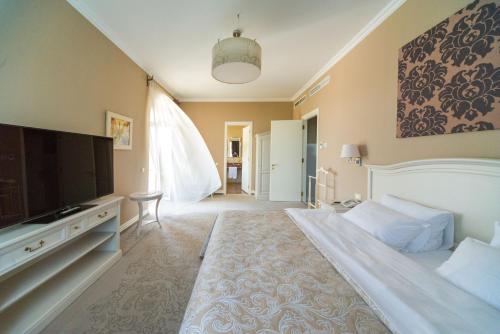 a bedroom with a large bed and a flat screen tv at Palace Del Mar in Odesa