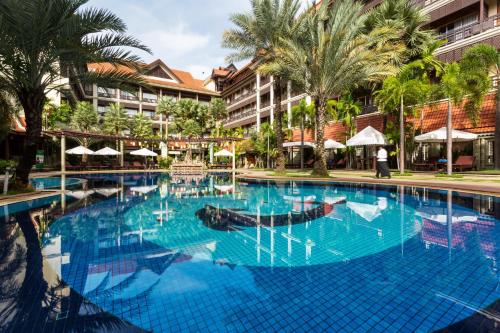 a swimming pool at a resort with palm trees at Empress Angkor Resort & Spa in Siem Reap