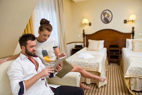 a man and a woman in a hotel room with a tablet at Hotel St. Bruno in Giżycko