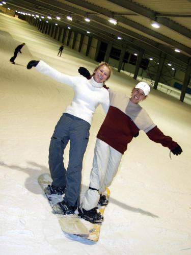a man and a woman standing on a snowboard at Hotel De Boskar Peer in Peer