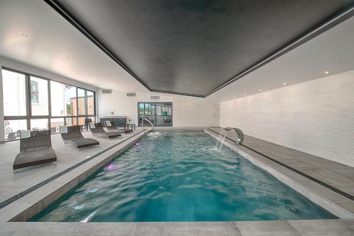 a swimming pool with chairs in a building at Logis Aux Maisons in Maisons-lès-Chaource