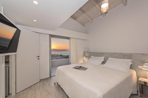 a bedroom with a white bed and a large window at Aenaon Seaview Villa in Platanias
