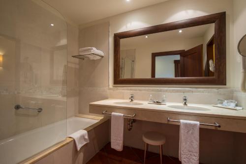 Un baño con lavabo, bañera y espejo. en Puerto Antilla Grand Hotel, en Islantilla