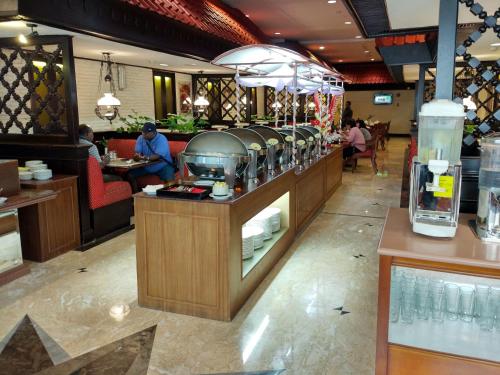 a restaurant with a food counter and people sitting at tables at Jayakarta Hotel Jakarta in Jakarta