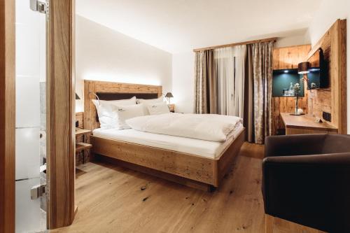 um quarto com uma cama com lençóis brancos e pisos em madeira em Hotel Spescha em Lenzerheide