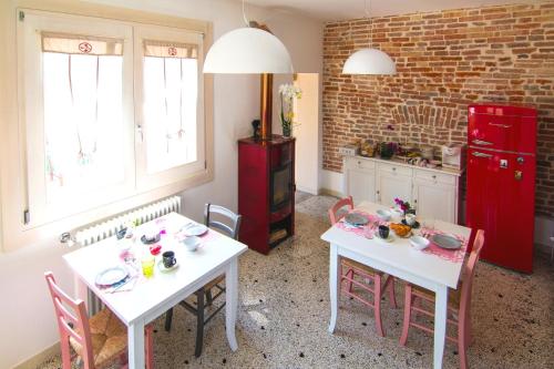 a kitchen with two white tables and a red refrigerator at B&B La Porta Rossa in Noale