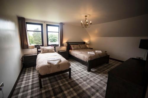 
a room with two beds and two windows at Whitehouse B&B in Fort Augustus
