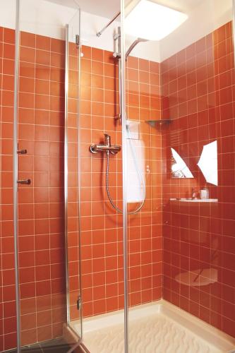 an orange tiled shower with a glass shower stall at Albergo Diffuso Zoncolan in Ovaro