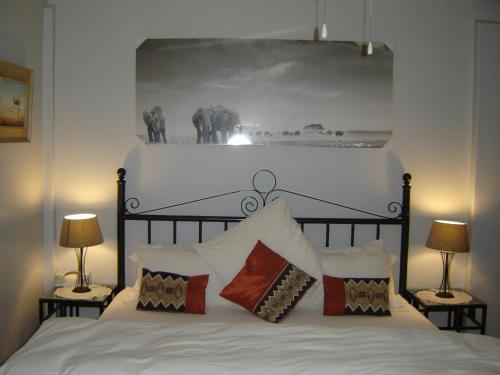 um quarto com uma cama branca e 2 candeeiros em Cedar Lodge Guest House em Robertson