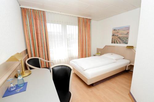 a room with a bed and a table and a window at Hotel Altbacher Hof in Altbach