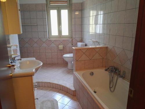 ein Badezimmer mit einer Badewanne, einem Waschbecken und einem WC in der Unterkunft Casa Catena in Francavilla di Sicilia