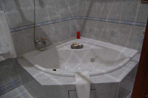 y baño alicatado con bañera blanca. en Falcon Crest Suites en Gaborone