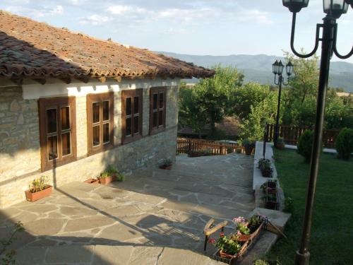 a stone house with a patio and a yard at Guest House Zarkova Kushta in Zheravna