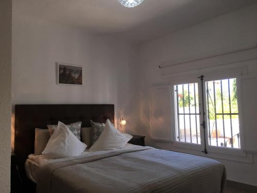 a bedroom with a bed with white sheets and a window at Vista Bahia II Apartments- top floor with balcony views & ground floor with garden and BBQ in Albir