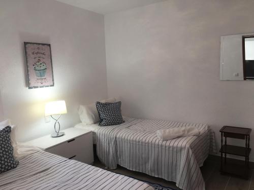 a bedroom with two beds and a lamp on a table at Vista Bahia II Apartments- top floor with balcony views & ground floor with garden and BBQ in Albir