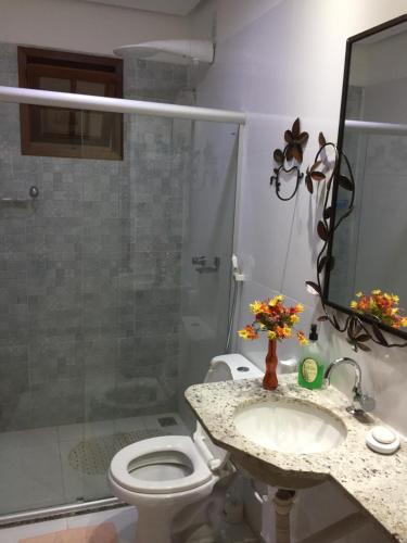a bathroom with a toilet and a sink and a shower at Apartamento 05 Vivendas do Serrano - Lençóis in Lençóis