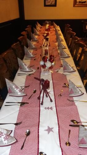 ローアにあるLandhotel Zur alten Postの赤白の皿、フォーク、包丁が並ぶ長テーブル