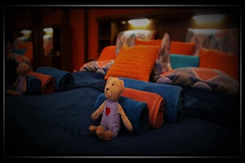 a teddy bear sitting on top of a bed at HAPPY COLOURS in Old Town in Kecskemét