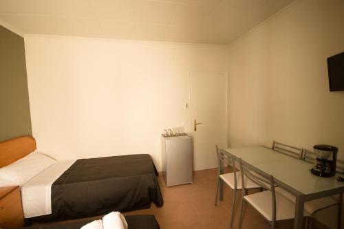 a small room with a bed and a table and a refrigerator at Center Plaza Figueres in Figueres